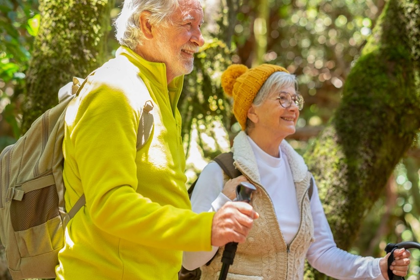 A cute elderly couple hiking in the mountains; they are so grateful that they used ROMTech portable Connect to help them recover from their total knee replacement.}